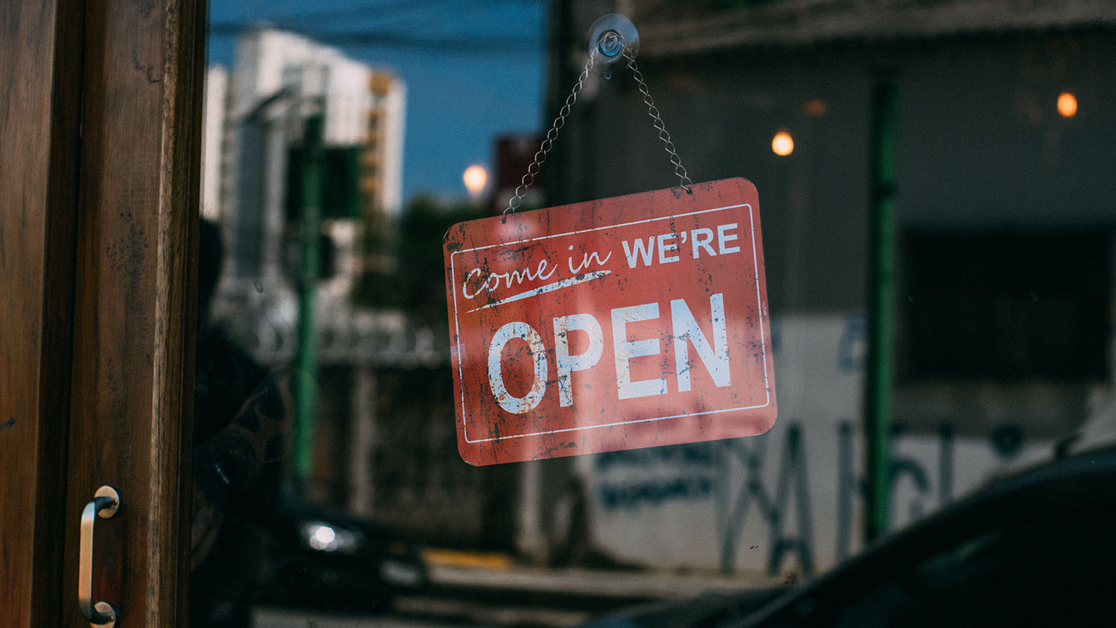 "Come in we're open" sign on storefront door