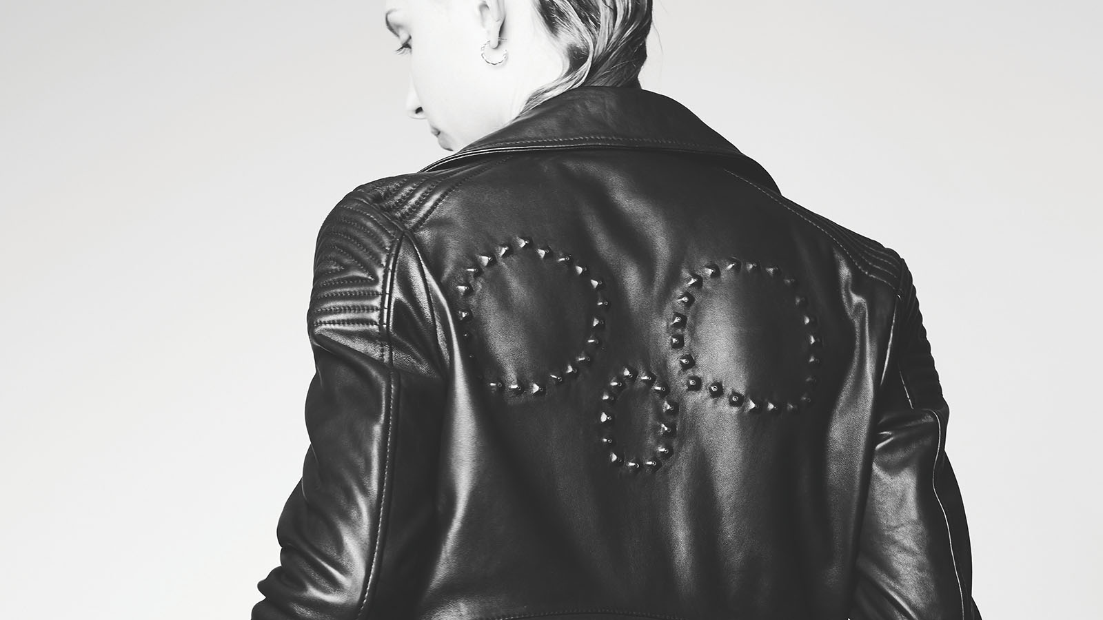 Person wearing leather jacket with a rhinestone skull on the back