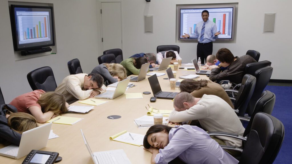 People sleeping during a presentation with the presenter acting frustrated in the background