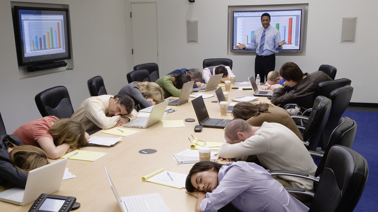 People sleeping during a presentation with the presenter acting frustrated in the background