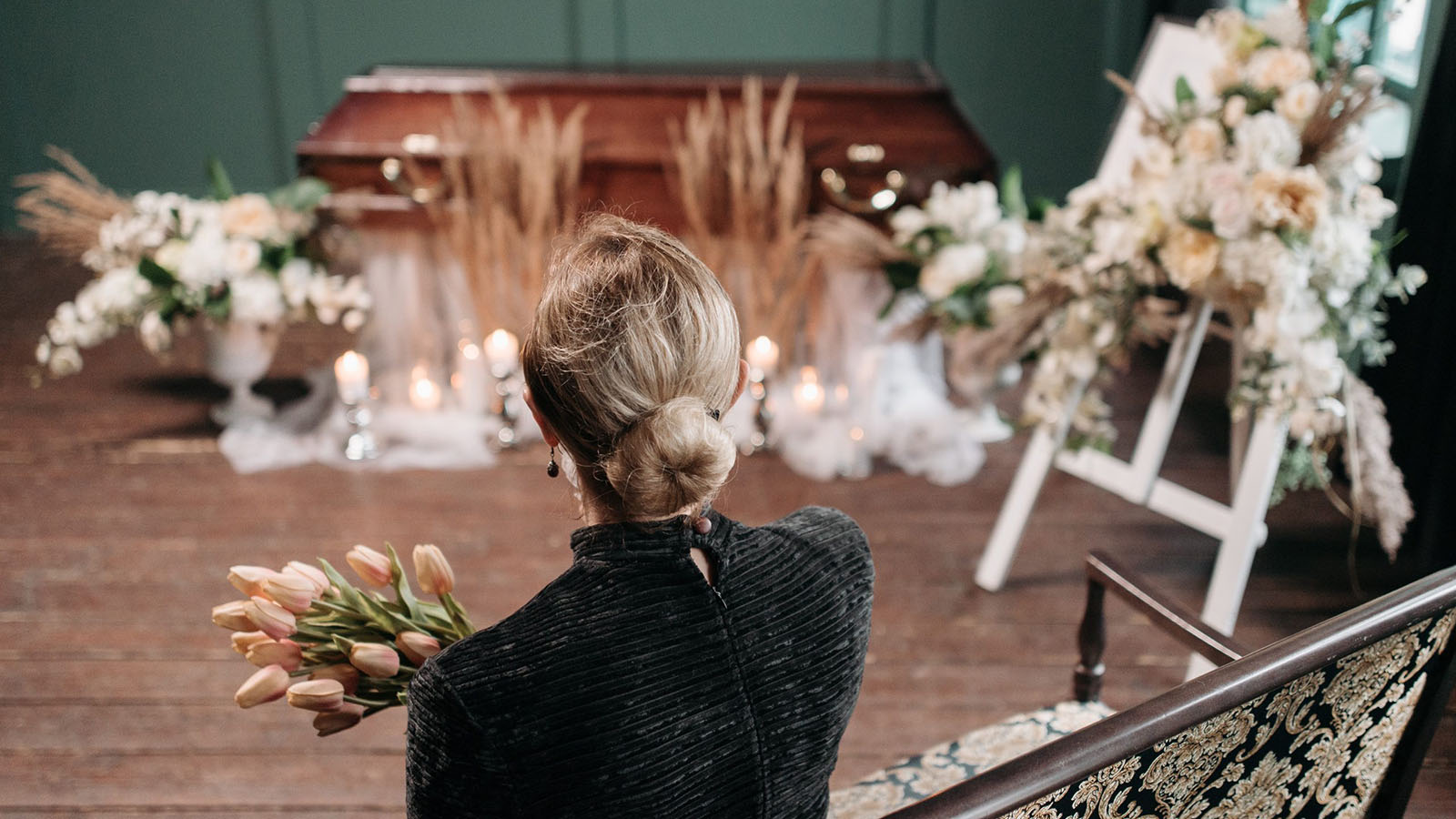 Women holding flowers looking at a closed casket