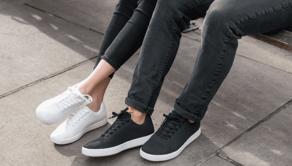 A view of two people's legs and shoes while they're sitting on a bench