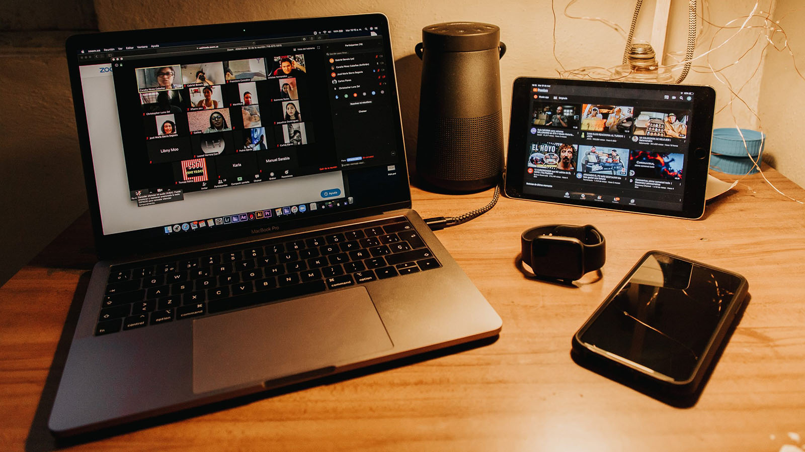 Zoom meeting on a laptop next to an iPhone and Apple Watch